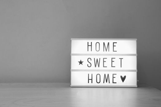 'Home sweet home' text in lighbox on wooden shelf, modern retro decoration purple wall