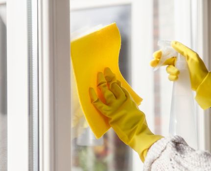 Cleaning a window with spray detergent, Yellow rubber gloves and dish cloth on work surface concept for hygiene, business and health concept home interior