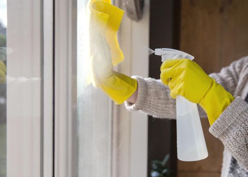 Cleaning a window with spray detergent, Yellow rubber gloves and dish cloth on work surface concept for hygiene, business and health concept home interior