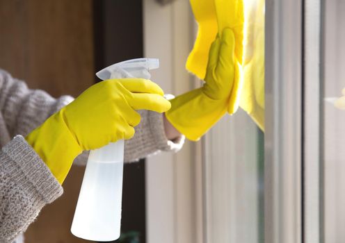 Cleaning a window with spray detergent, Yellow rubber gloves and dish cloth on work surface concept for hygiene, business and health concept home interior