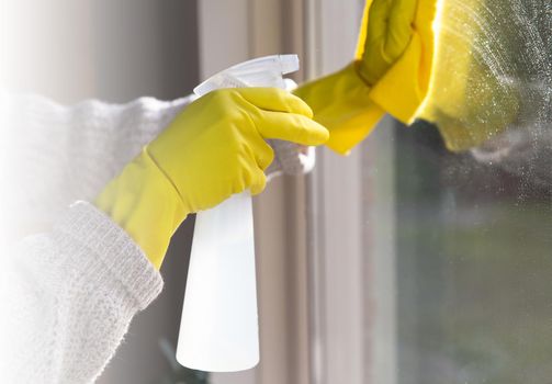 Cleaning a window with spray detergent, Yellow rubber gloves and dish cloth on work surface concept for hygiene, business and health concept home interior