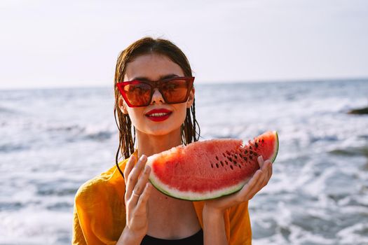 woman on the beach near the ocean eating watermelon. High quality photo