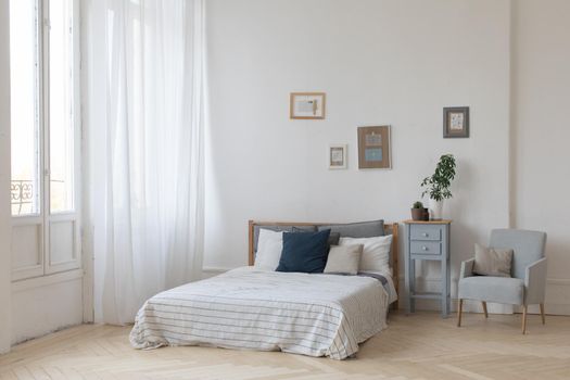 Interior of white and gray cozy bedroom with plants on the bedside table