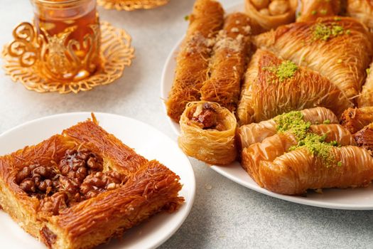 Various Turkish sweets and cup of tea on white textured background, close up