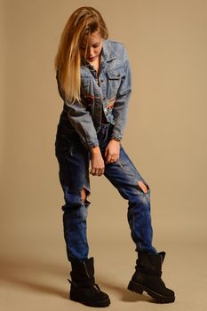 teenage girl in jeans stands looking down on gray background