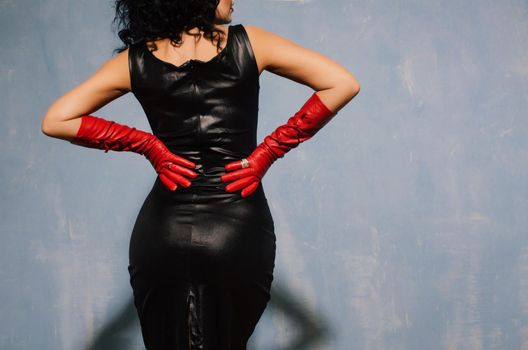 Beautiful fetish model wearing black spandex dress and long red leather gloves back.