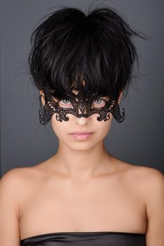 Beautiful young woman in black mysterious lace venetian mask. Fashion photo