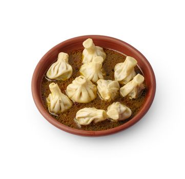 Portion of khinkali on clay plate isolated on white background, close up