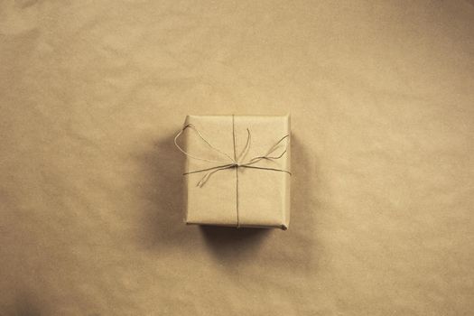 Two gift boxes wrapped in plain brown recycled paper with rope on brown background texture top view, present and recycle concept, copy space, space for text retro