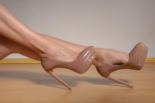 woman shapely legs wearing brownlacquered high heel shoes. Close up view