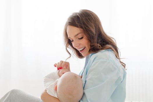 Happy young woman holding on hands her infant child.