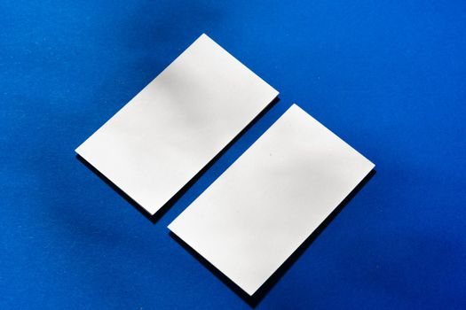 Two stacks of blank businesscards on blue background close up