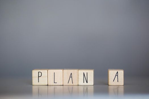Wooden cube with PLAN A text on grey background. Goals, success, strategy, solution and business concepts close-up