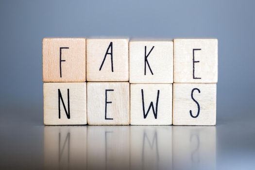 Wooden cubess with the words Fake News on grey background, Fake News concept social media close-up