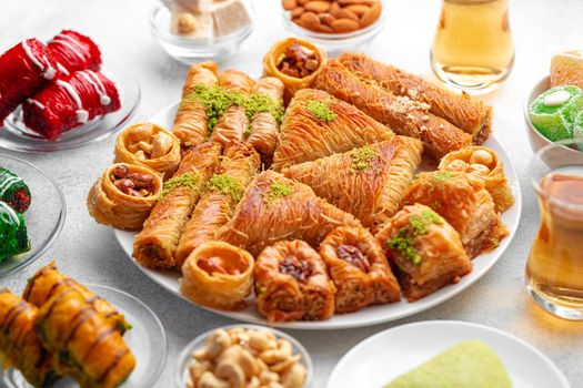 Various Turkish sweets and cup of tea on white textured background, close up