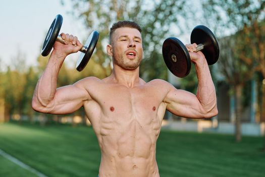 sporty man with pumped up body in park workout exercise. High quality photo