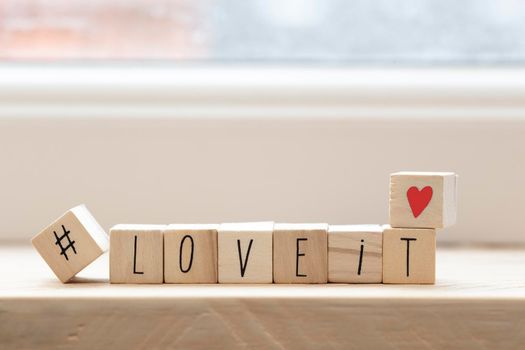 Wooden cubes with a hashtag and the words love it, social media concept background beauty