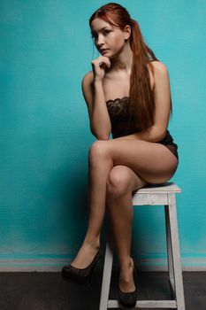 girl in underwear sitting on a stool against the blue wall