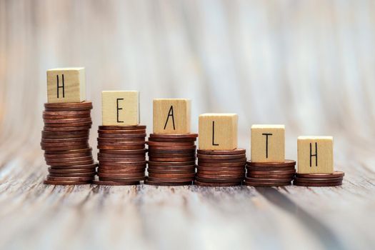 Word HEALTH on step stacked coins as graph up with white background. Money savings or investment planning for life insurance and healthcare concept.