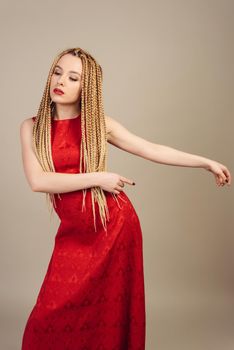 beautiful young woman dressed in a red dress points with his hands to the side.