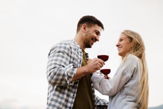 Smiling couple toasting wine glasses outdoors in mountains, close up portrait