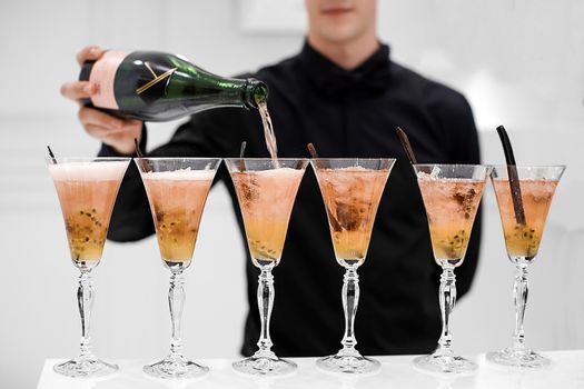 Crop view of faceless waiter in black shirt making alcoholic cocktails and adding champagne in glasses