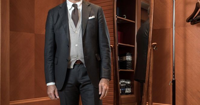 Unrecognizable man in stylish suit standing in closet room.