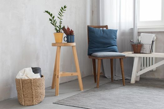 Interior of room with cute chair and stool with potted plant.