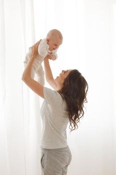 Cheerful woman playing with adorable infant child.