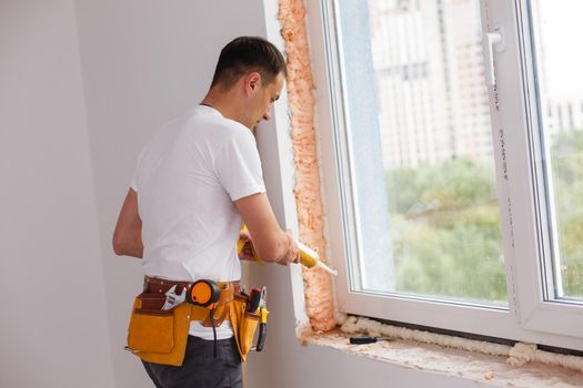 Man putting filling between window and wall in a new house