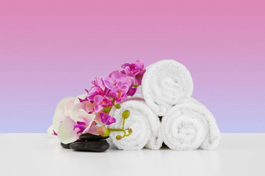 Beautiful pink flowers and white towels on pink background, front view