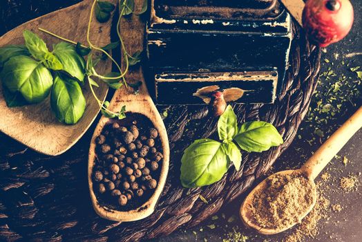 old mill and wooden spoons with spices on a black table