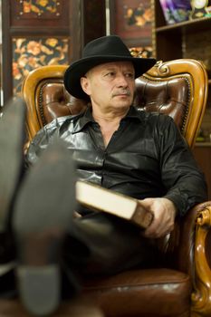 Elderly man in a hat in a leather chair