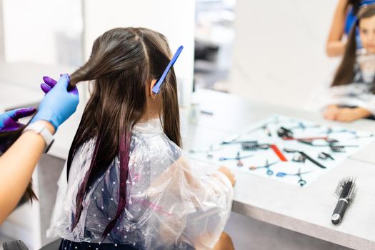 hairdresser dyes hair for a little girl in a hair salon. Dyed, bleached hair