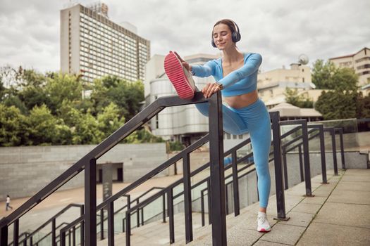 Beautiful fit caucasian woman is doing exercises outdoors at the city