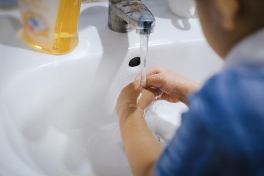 Little boy washing his hands with soap to clean the germs from corona virus