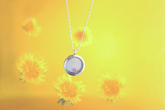 Silver necklace for her shining on yellow background with dandelions. Luxury silver jewelry chains with glass and crystals. Small Beautiful precious metal present for woman.