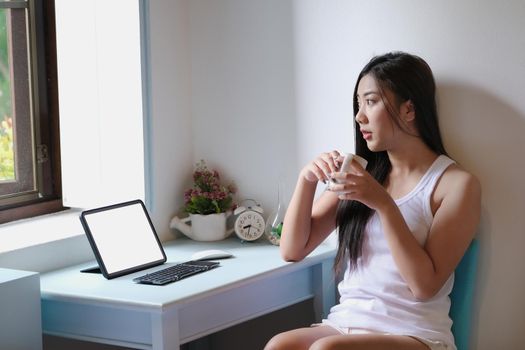 new normal, a businesswoman using tablet to work for a company Via the internet on your desk at home