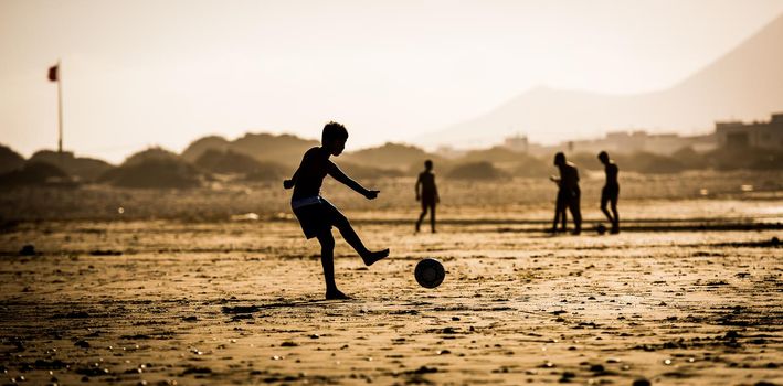 Silhouette of the boy on the beach with a ball