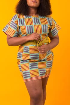 Young beautiful african american girl with an afro hairstyle. Portrait on yellow background.