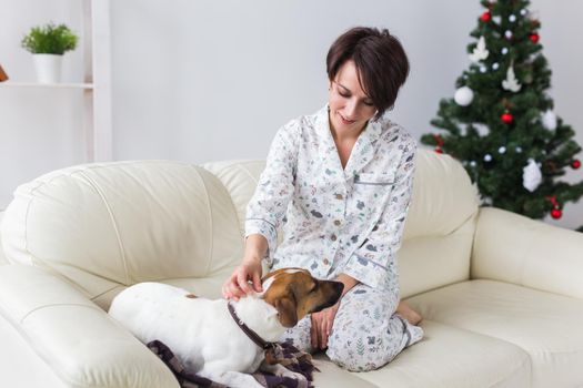 Happy young woman with lovely dog in living room with christmas tree. Holidays.