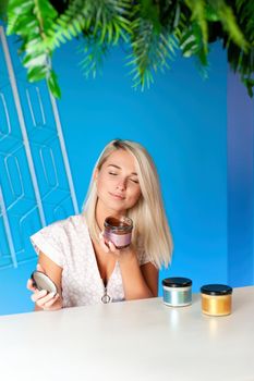 Blonde woman sits at a table with vegan paste in jars
