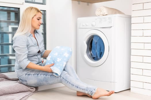 A young housewife with washing machine and clothes. Washing day.