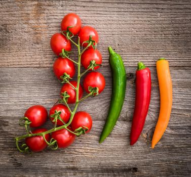 cherry tomatoes and chilli pepper on a wooden background