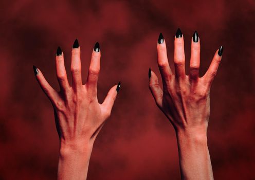 Red hands of the devil on background of fire. Halloween or horror theme