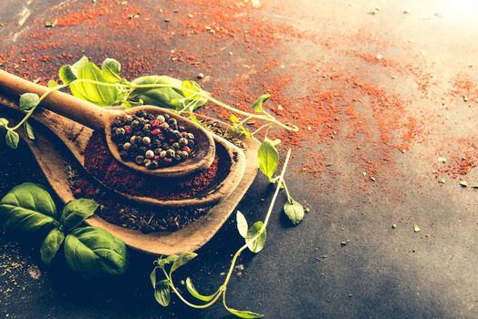 wooden spoons with spices and herbs on textured black background