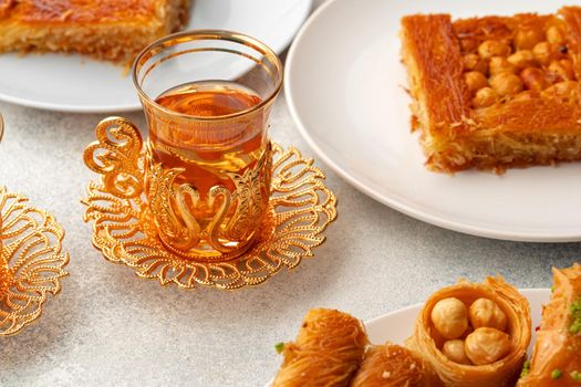 Various Turkish sweets and cup of tea on white textured background, close up