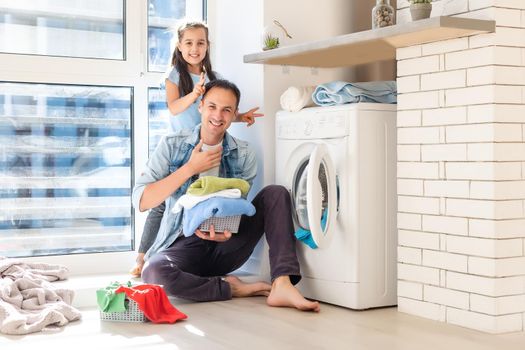 Happy Family loading clothes into washing machine in home