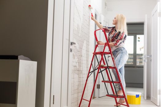 happy woman makes repairs in room at home