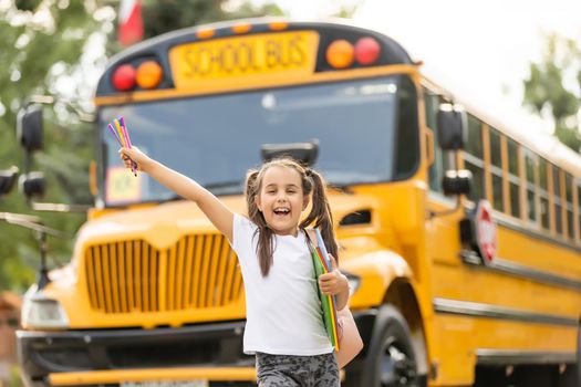 Cute girl with a backpack standing near bus going to school posing to camera pensive close-up